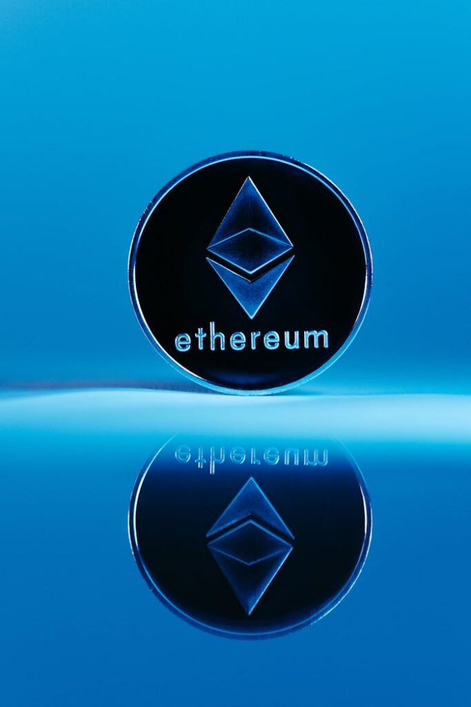 Ethereum coin standing with reflection on a blue surface, symbolizing cryptocurrency innovation.