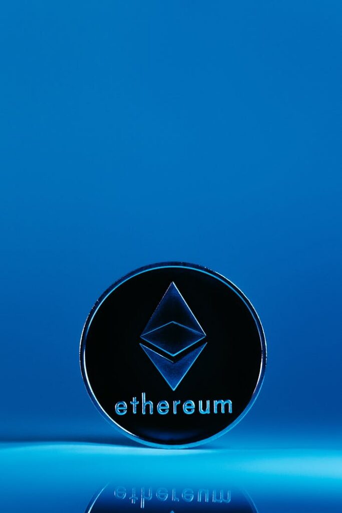 pexels photo 14911400 A vertical shot of an Ethereum coin standing on a reflective surface with a blue background.