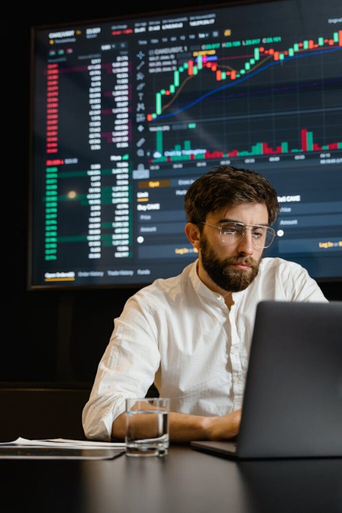 pexels photo 7567523 A man analyzing cryptocurrency trends on a laptop with trading graphs displayed on a screen.