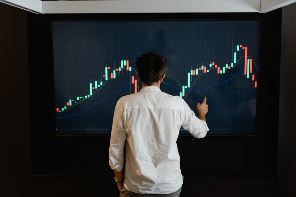 pexels photo 7567591 Adult male reviewing stock market data on a large display screen indoors.